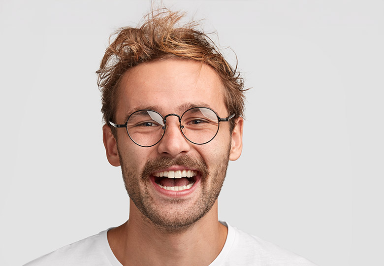Lachender Mann vor grauem Hintergrund. 